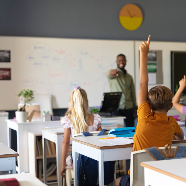 African american young male teacher pointing on multiracial elementary students with hand raised. unaltered, education, learning, childhood, teaching, occupation and school concept.